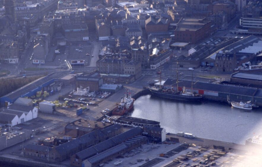 Picture offers an aerial view of Dundee Harbour showing boats and warehouses