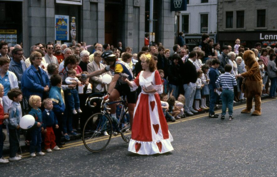 A woman dressed as queen of hearts hands out sweets.
