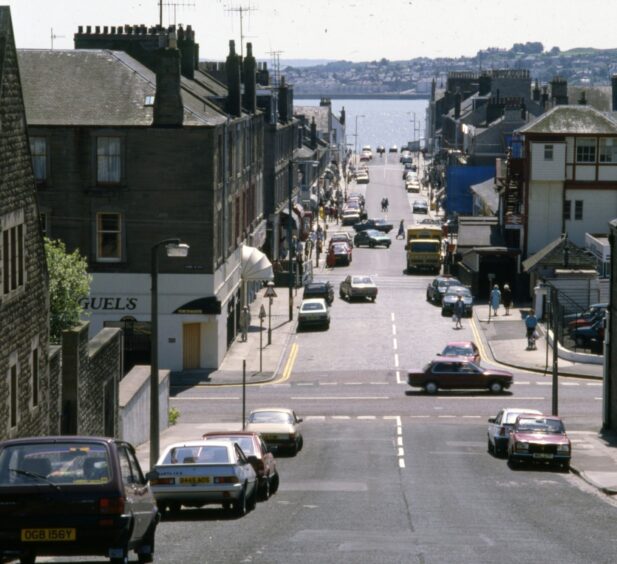 Looking down Gray Street and over the level crossing in 1988. There are cars parked on the road and the River Tay is in the distance