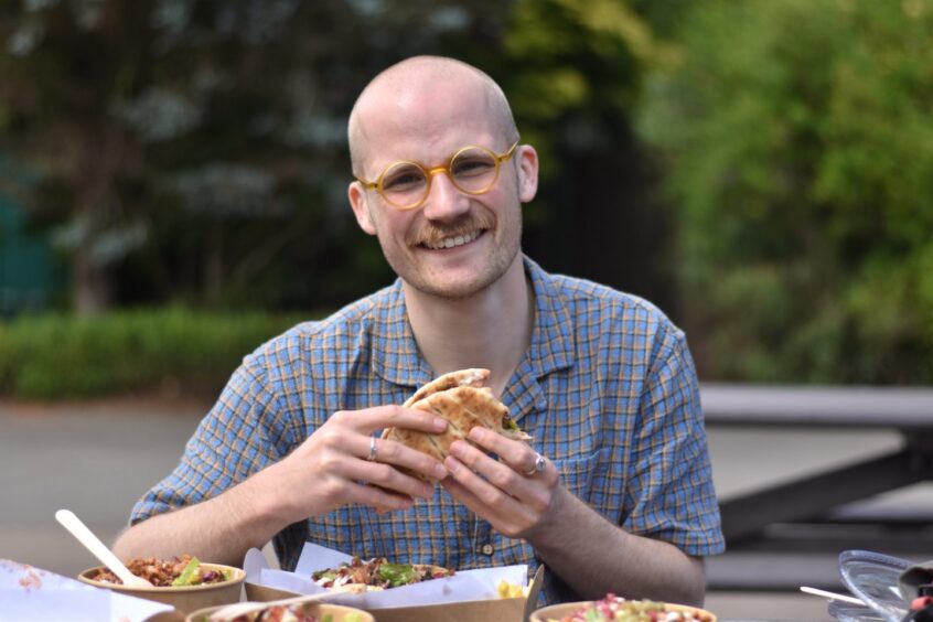 Jacob Smith holding a shawarma and smiling at Craigtoun Country Park, Fife.