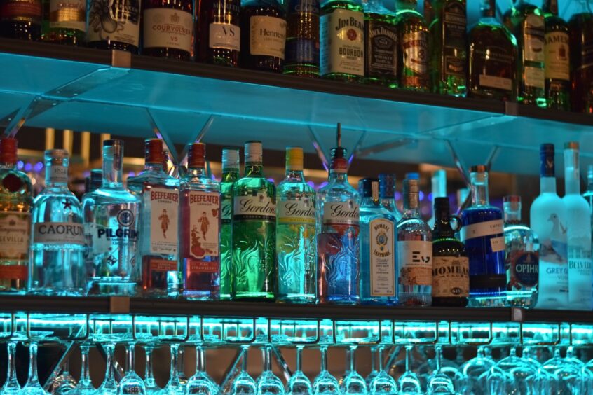 Bottles of spirits arranged on the back of a bar in 1876.