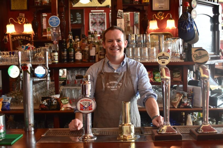 A smiling Jonathan Stewart owner of The Speedwell Bar, standing behind the bar