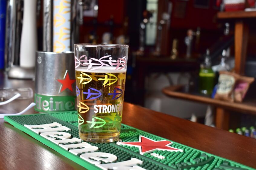 A pint of cider sitting on a bar.