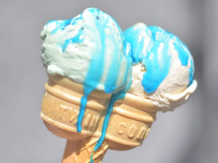 A double ice cream cone, melting in the sun with blue syrup on it.