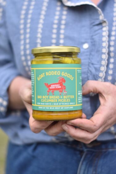 A woman holding a jar of pickles.