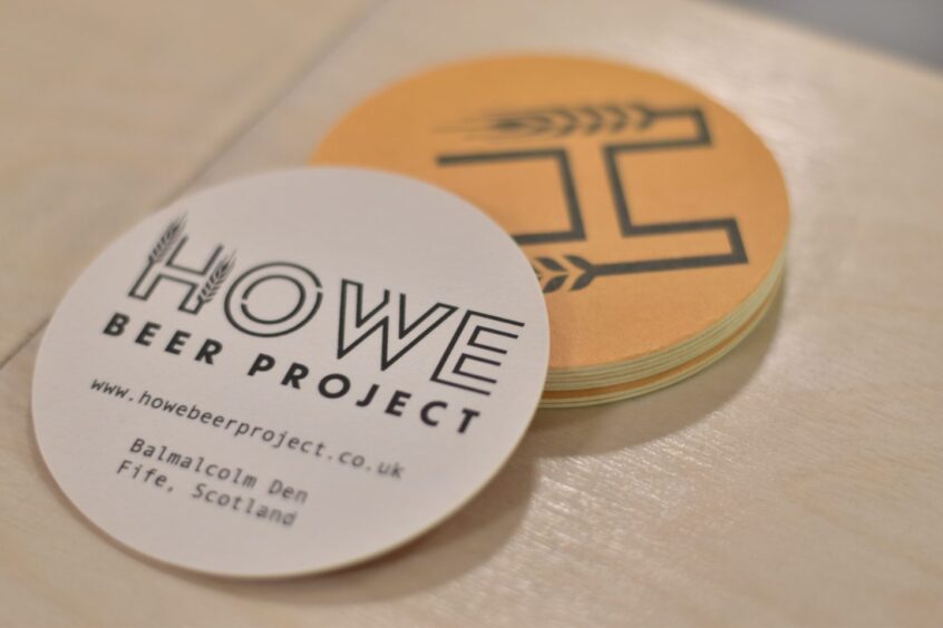 Howe Beer Project-branded beer mats sitting on a bar.