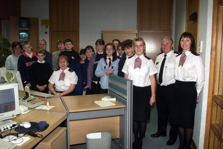 Pupils with control room staff gathered around a desk