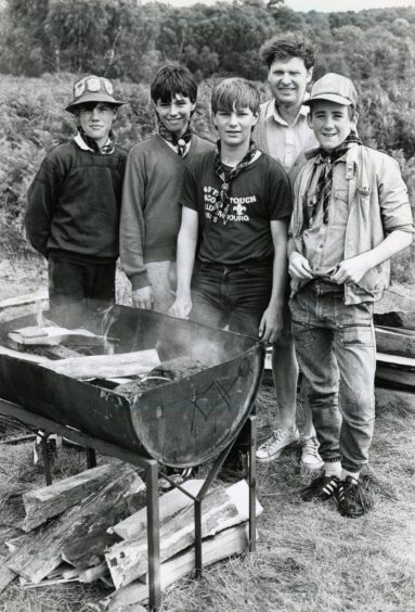 A group of Scouts standing next to an open fire in July 1986.