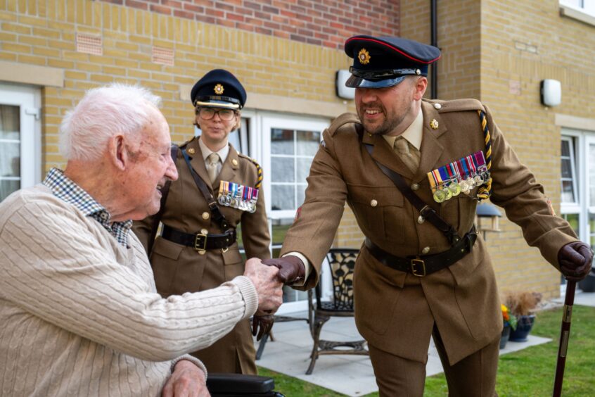 Walter Smith shaking hands with man in uniform and lots of medals