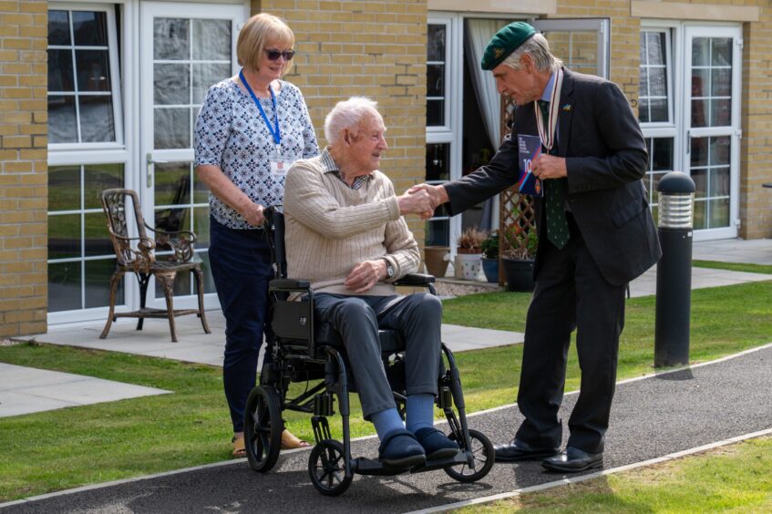 Walter Smith in wheelchair accepting card from man, while daughter stands behind chair