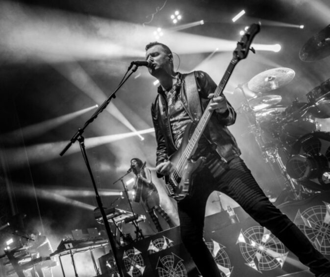 Ged Grimes on stage with Simple Minds.