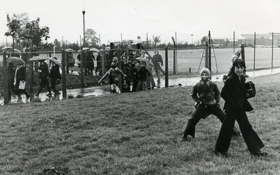 Pupils take a shortcut through a gap in the fence in August 1977.
