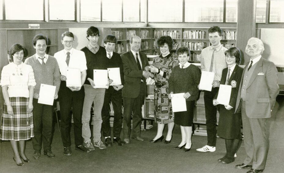 Staff join Gavin Smith as he presents Duke of Edinburgh award certificates to pupils in the library in May 1986.