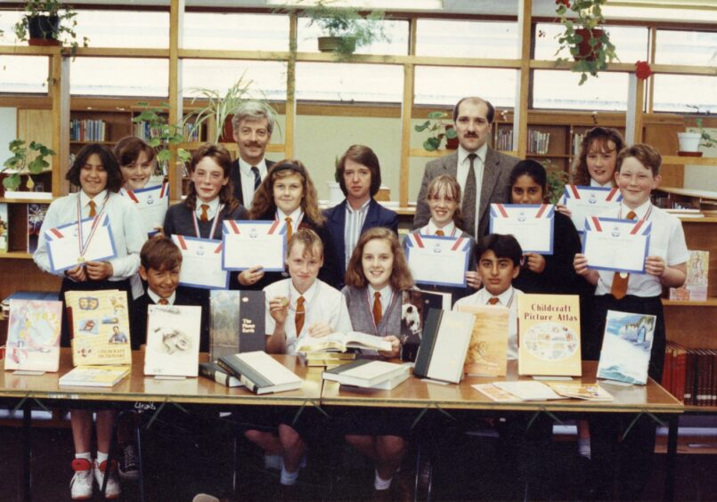 Staff and Sponsored reading participants behind a desk with books and their certificates