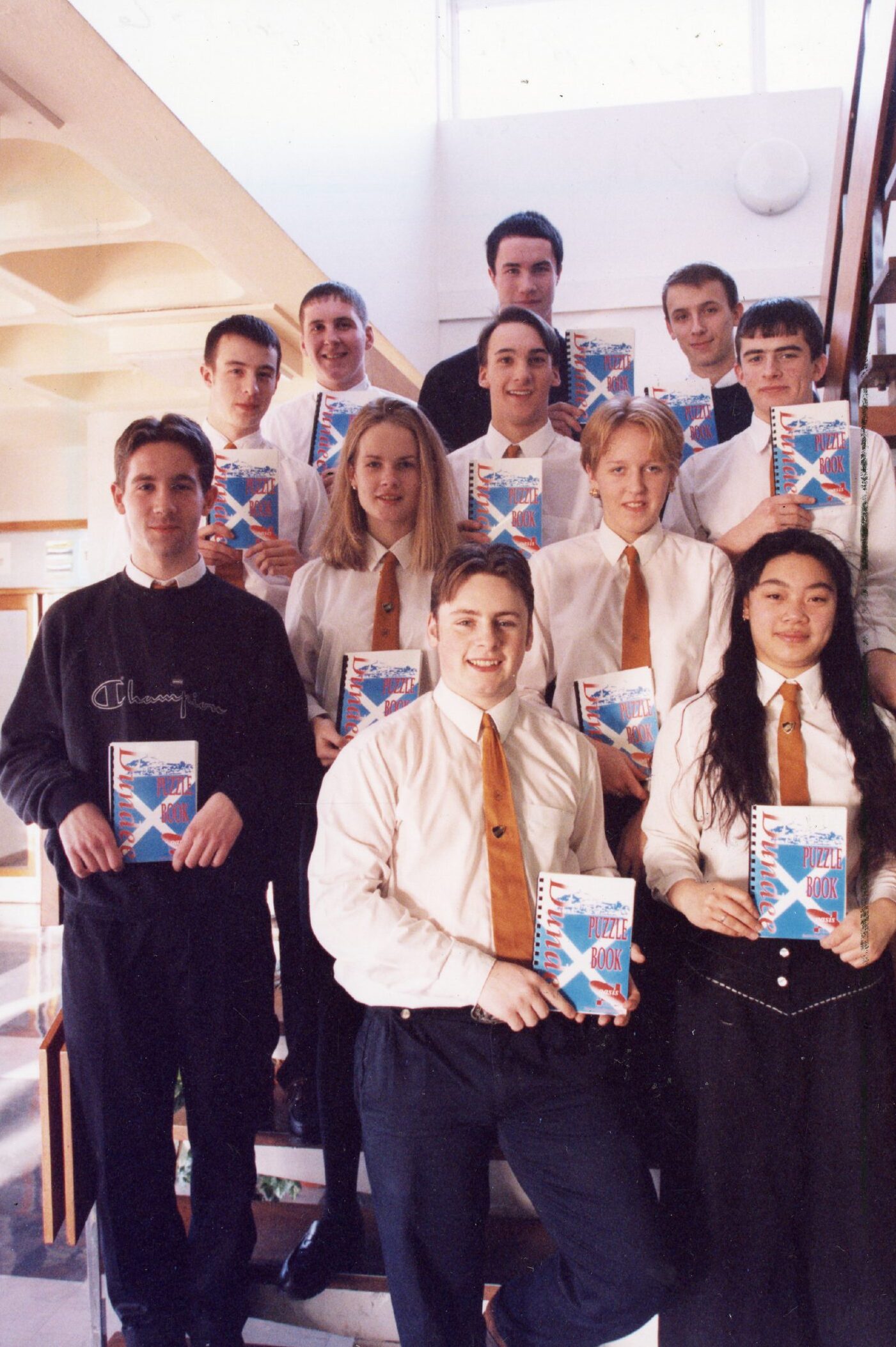 Craigie pupils stand on a stairway holding the puzzle books.