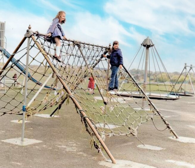 Two girls on cargo net at a playground.
