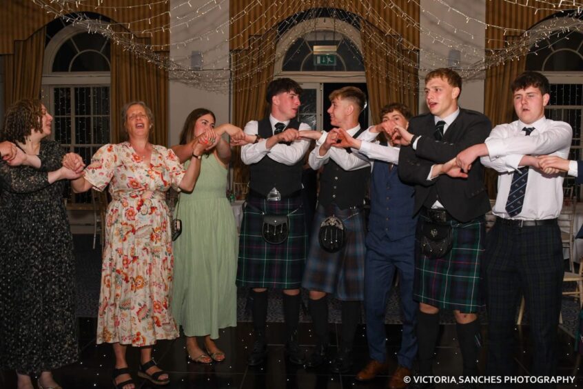 Departing pupils and teachers link hands on the dancefloor. 
