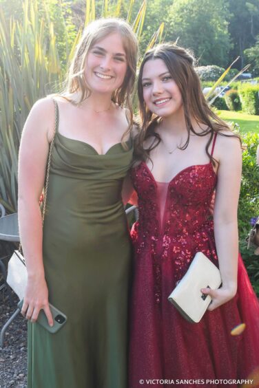 Two elegantly dressed girls standing outside. 