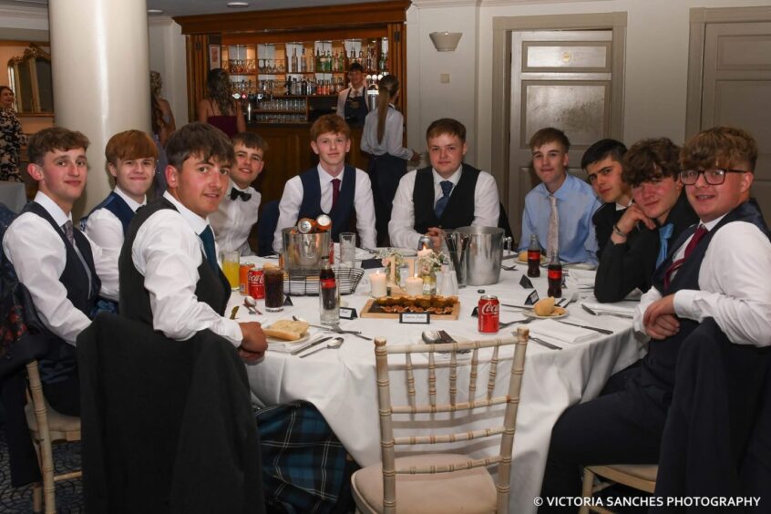 Smartly dressed boys around a circular table looking towards the camera. 