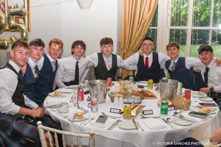 Smartly dressed boys around a circular table looking towards the camera. 