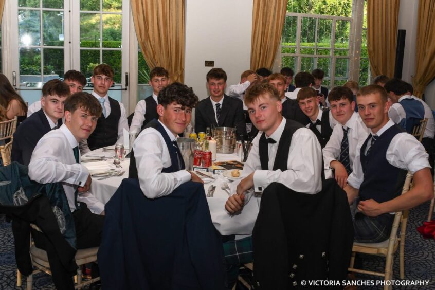 Smartly dressed boys around a circular table looking towards the camera. 