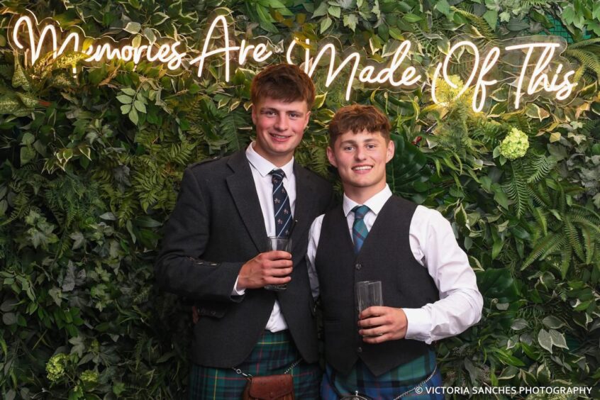 Two boys posing with a drink in hand. 