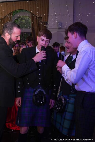 A boy in Highland dress speaks into a microphone. 