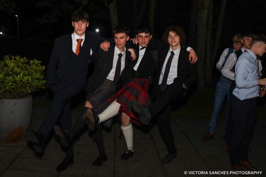 Four boys smiling at a school leavers' prom. 