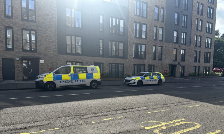 A police car and van outside a block of flats on Strathmartine Road in Dundee, where two men were arrested.