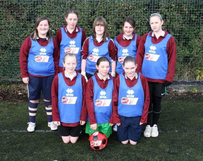 Eight members of the girls team with bibs and a ball