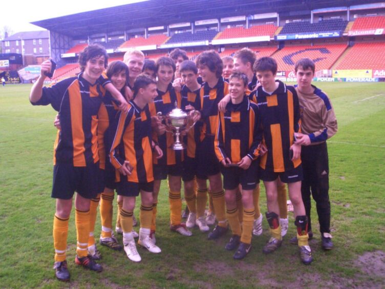 Craigie High players celebrate with the trophy on the pitch at Tannadice Park