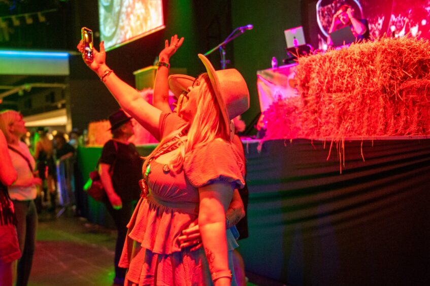 Two female friends in cowboy hats take a selfie in a nightclub. 