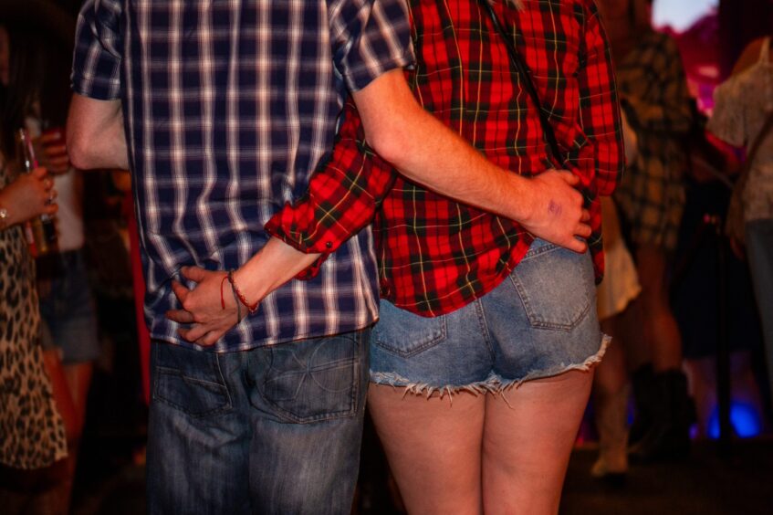 A man and woman pictured from behind with a hand on each other. 