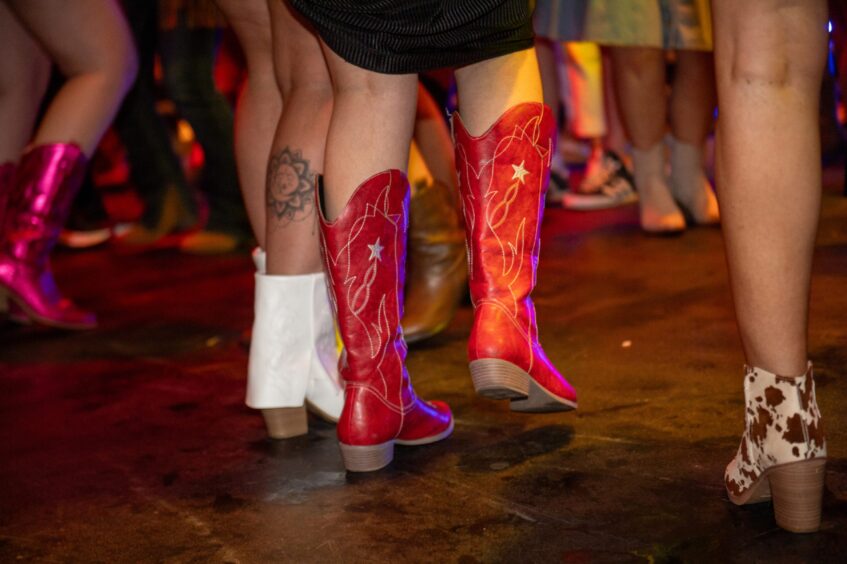 Close-up of cowboy boots worn by party-goers. 