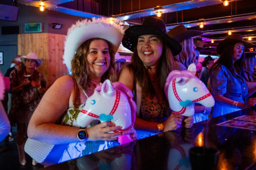 Two women in cowboy hats in a nightclub. 