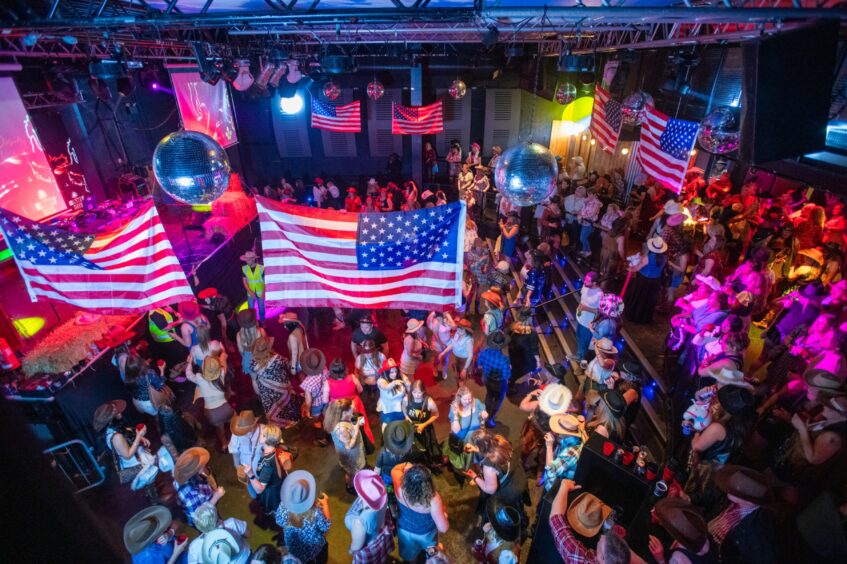 A packed dancefloor decorated with large USA flags. 