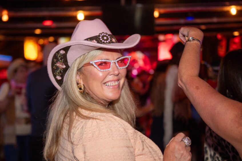 A woman in a cowboy hat and red-lensed flamboyant glasses. 