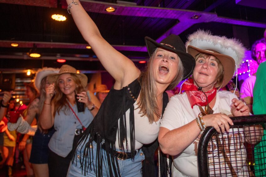 Women in country and western garb in a nightclub. 