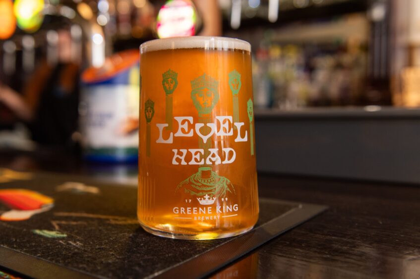 A pint of beer sitting on a bar.