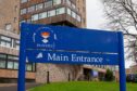 a sign stating main entrance to Dundee University, with a building in the background