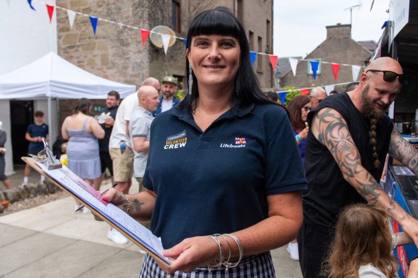 A woman in a navy polo shirt holding a clipboard. 