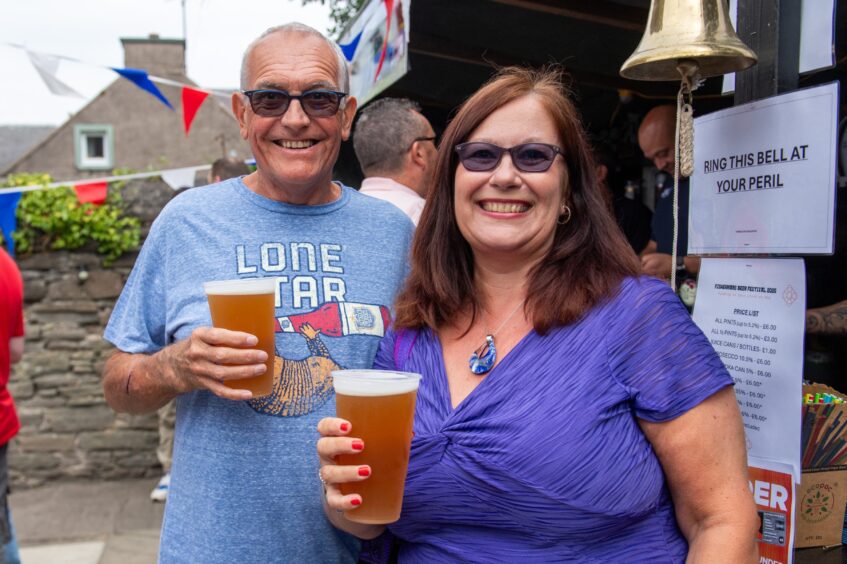 A man and a woman, both in sunglasses and clutching drinks. 