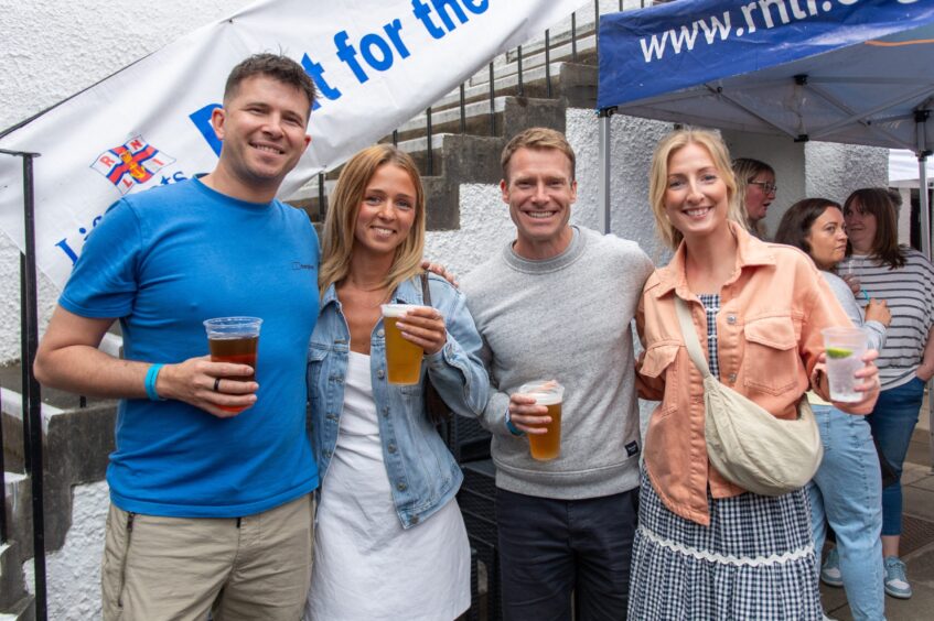 Two men and two women clutching drinks at a beer festival. 