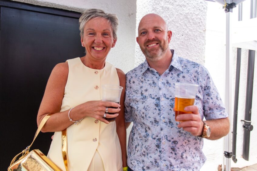A man and a woman, both clutching a drink. 