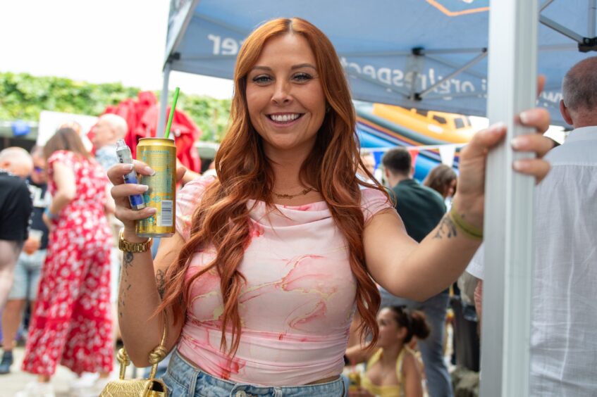 A woman with long, red hair clutching a drink. 