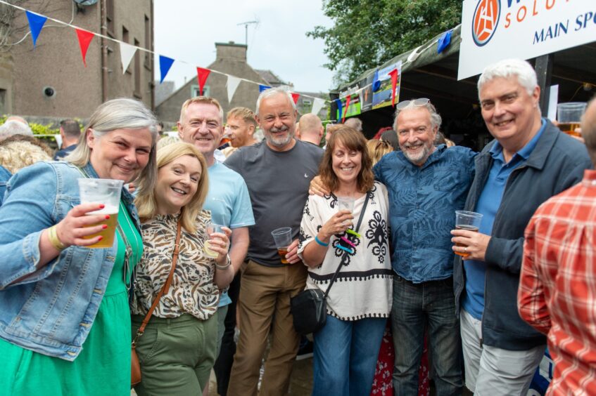 Crowds enjoy a drink under some bunting. 