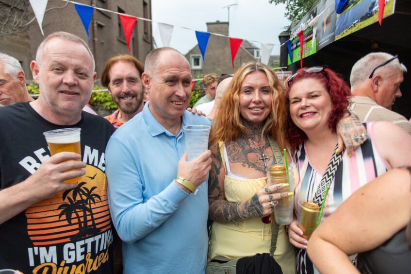 Two men and two women, all in summer clothes and clutching a drink. 