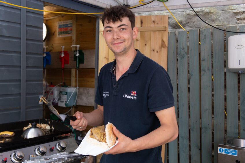 A man flipping burgers on a barbecue. 