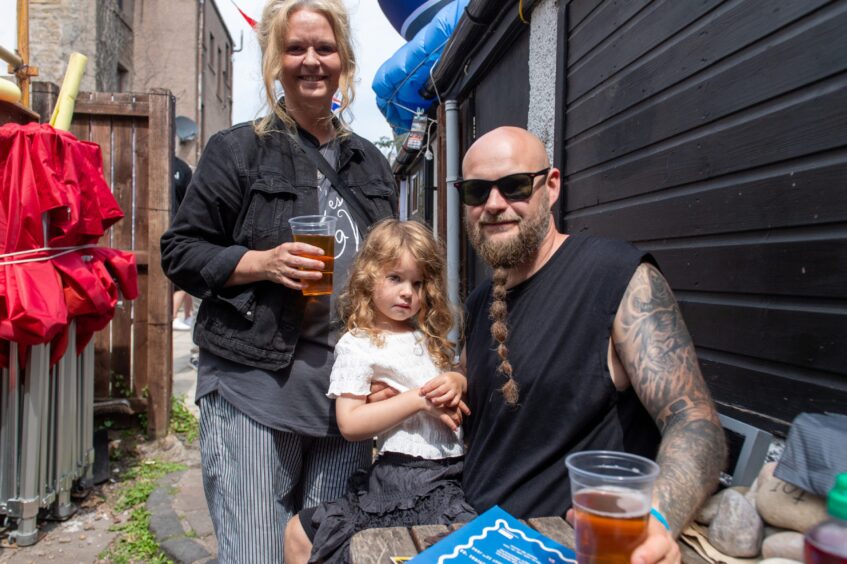 A man, woman and young girl at a beer festival. 