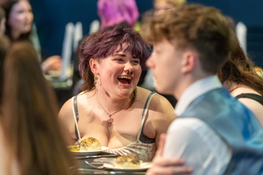 A girl laughs at the table.